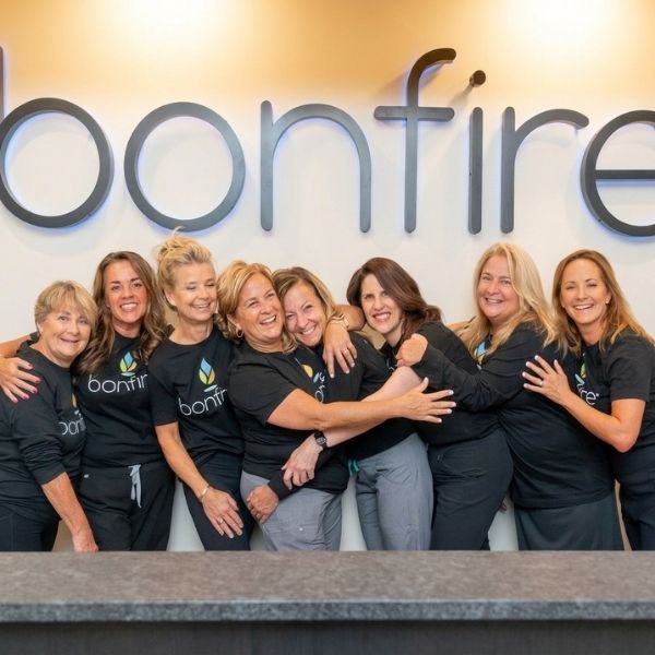 A group photo of the Bonfire Wellnes crew members in front of their logo.