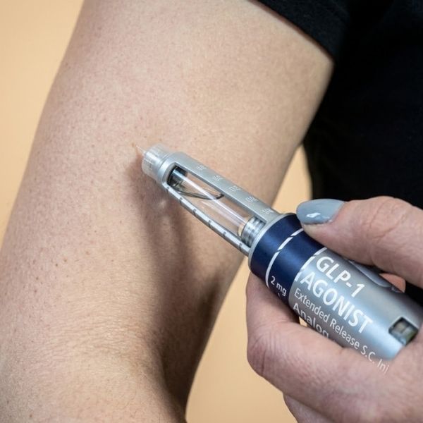 A woman giving herslef a GLP-1s injection.
