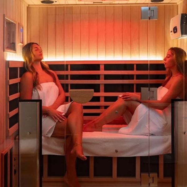 Two women relaxing inside a wooden infrared sauna during an ir sauna therapy session at Bonfire Wellness