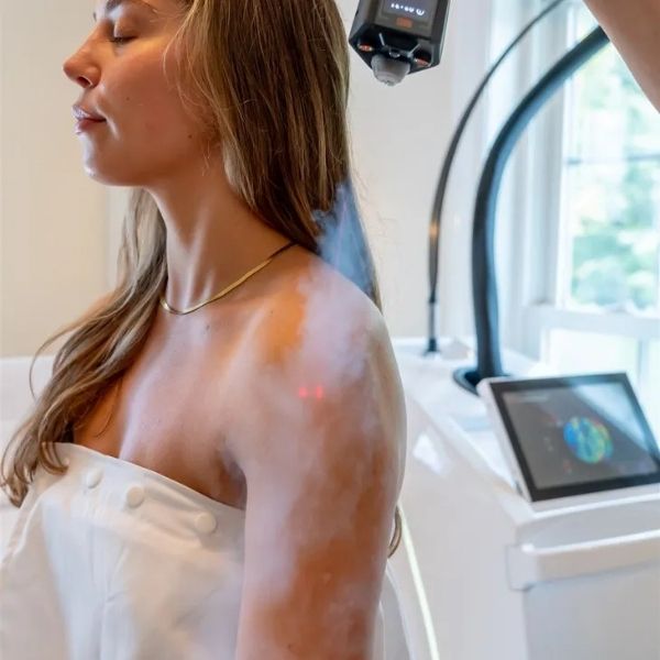 A woman receiving a localized cryotherapy procedure on her shoulder and arm.