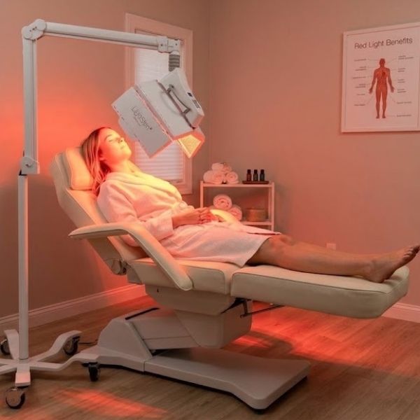 A woman relaxing while receiving a red light facial therapy session at Bonfire Wellness.