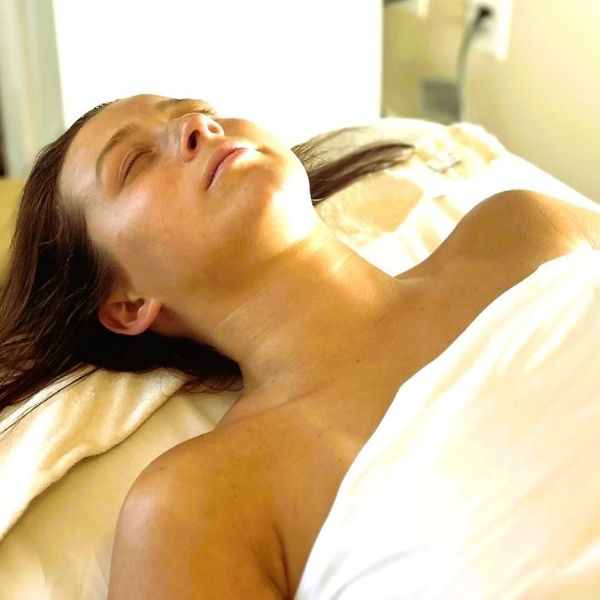 A woman laying down and relaxing during a holistic wellness facial procedure at Bonfire Wellness.